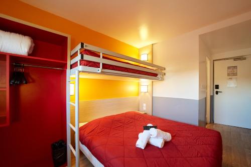 two stuffed animals sitting on top of a red bed at Première Classe Amiens in Amiens