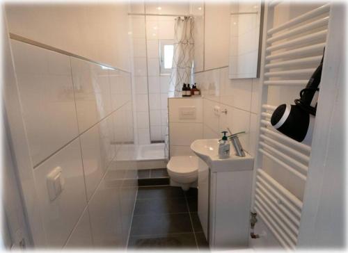 Baño blanco con aseo y lavamanos en Altbaucharme! 2Zimmer, zentral und 24h Check-in, en Kiel