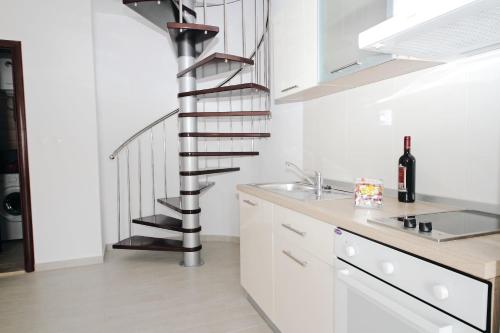 una escalera de caracol en una cocina blanca con fregadero en Apartments Du Lux en Mokošica