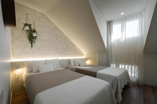 two beds in a hotel room with white walls at APARTAMENTOS TURISTICOS QUINTA LA PLAZA in Quintanadueñas