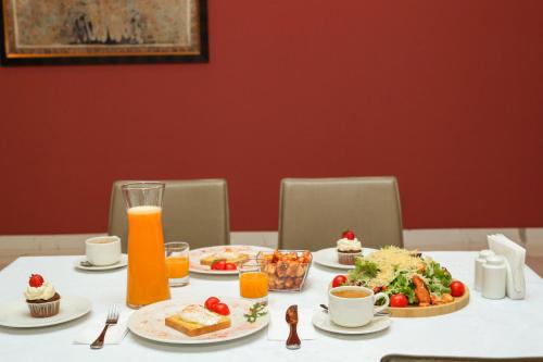 Una mesa con alimentos para el desayuno y jugo de naranja sobre ella. en Pine Astoria Hotel, en Tiflis