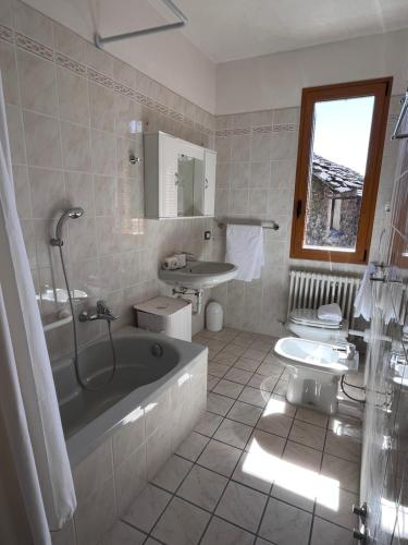 a bathroom with a tub and a toilet and a sink at Casa Marcela in Gravedona