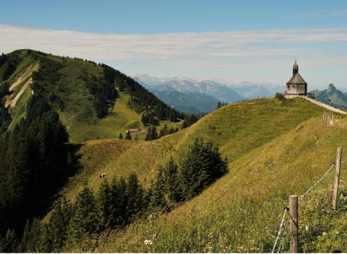 a church on top of a grassy hill at Berghotel Altes Wallberghaus in Rottach-Egern