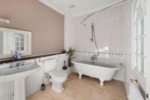 a white bathroom with a tub and a toilet and a sink at Ashley House in Dundee