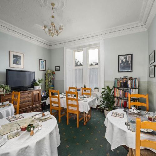 Un comedor con mesas y sillas y un televisor. en Ashley House, en Dundee