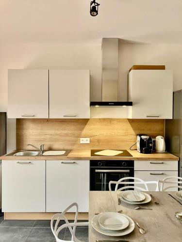 une cuisine avec des armoires blanches et une table et des chaises dans l'établissement tytoun evasion, à Borgo