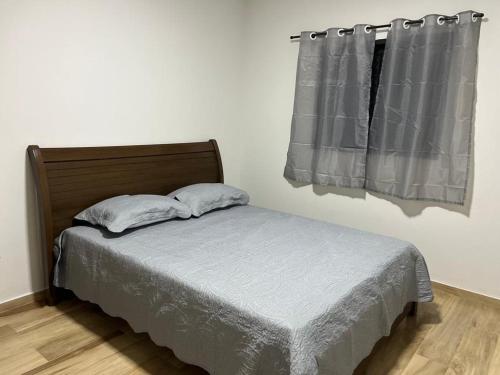 a bed with two pillows in a bedroom with a window at Casa Confortável e Aconchegante in Brotas