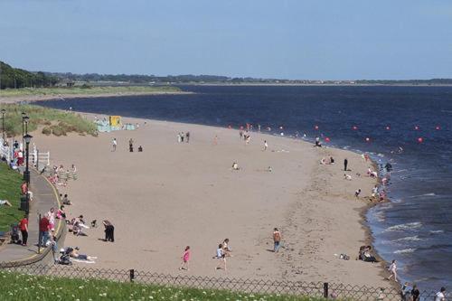un gruppo di persone su una spiaggia vicino all'acqua di Ashley House a Dundee