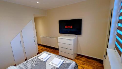 a bedroom with a bed and a tv on the wall at Private Room in Modern Apartment in Aberdeen