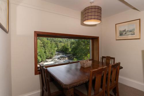 a dining room with a table and a window at Gatehouse, Bridge of Balgie, Glenlyon 