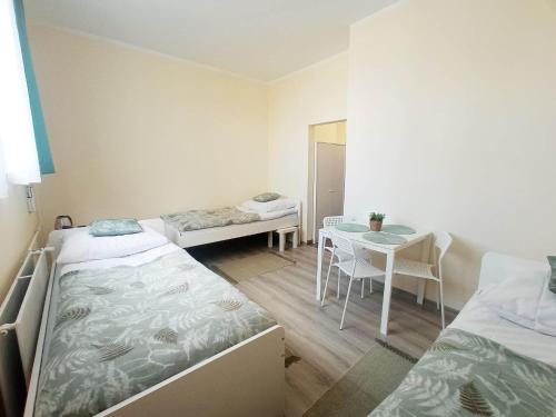 Cette chambre comprend deux lits, une table, une table et des chaises. dans l'établissement BOSiR Białogard, à Białogard