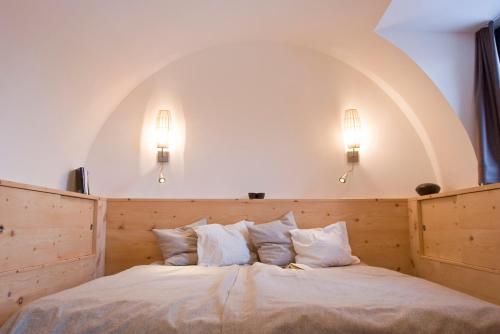 a bedroom with a large white bed with two lights at Gurgltal Refugia in Tarrenz