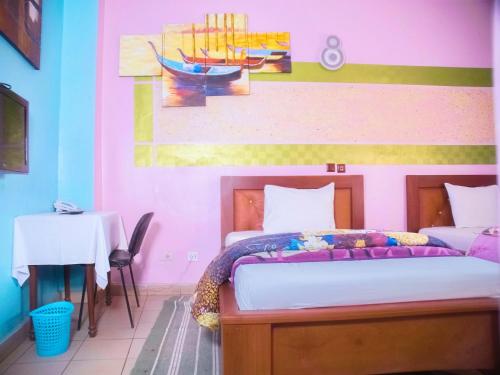 ein Schlafzimmer mit einem Bett und einem Gemälde an der Wand in der Unterkunft HOTEL DE LA VALLEE NEW in Jaunde