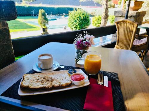 una mesa con un plato de comida y un vaso de jugo de naranja en Hotel Rural Spa & Wellness Hacienda Los Robles, en Navacerrada