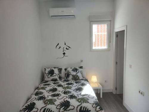 Schlafzimmer mit einem Bett mit einer schwarzen und weißen Bettdecke in der Unterkunft Cool Space in Madrid