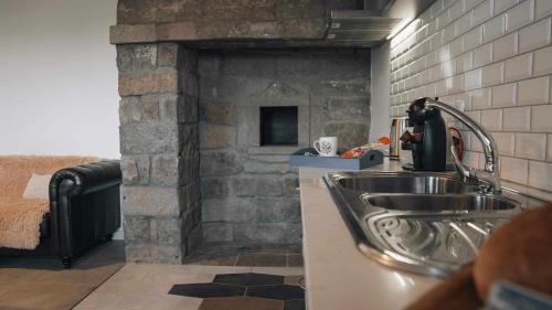 a kitchen with a sink and a brick fireplace at Casas do Forneiro A Casa Para 2 Pessoas in Nordeste