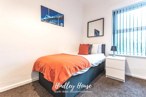 1 dormitorio con 1 cama con manta naranja en Hindley Serviced Accommodation en Hindley