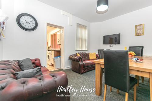 a living room with a couch and a table and a clock at Hindley Serviced Accommodation in Hindley