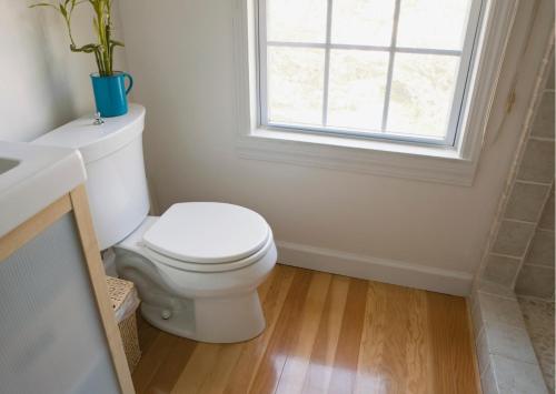 a bathroom with a white toilet and a window at Zingle Stay Airport Hotel in Chennai