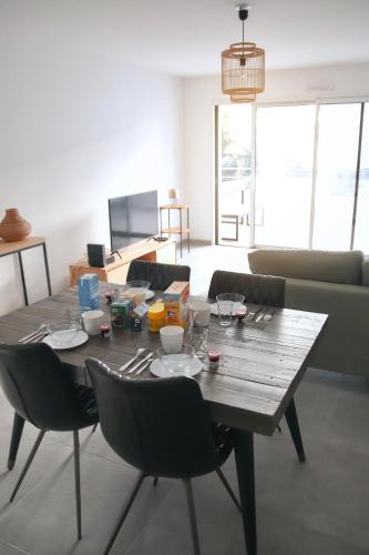 een houten tafel in een woonkamer met stoelen bij T3 30 dans résidence neuve près des plages in Saint-Cyr-sur-Mer