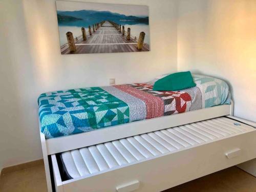 Una cama con una colcha junto a un muelle. en Apartamento Gandia muy cerca de playa con piscina en Playa de Gandia
