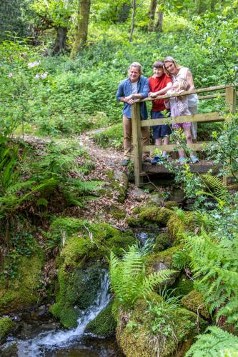 three people standing on a bridge over a stream at Aberdunant Hall in Porthmadog