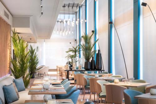 a restaurant with tables and chairs and plants at Salles Ciutat del Prat Barcelona Airport in El Prat de Llobregat