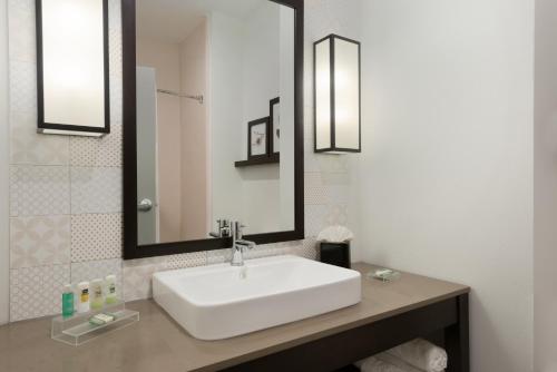 y baño con lavabo blanco y espejo. en Country Inn & Suites by Radisson, Katy (Houston West), TX en Katy