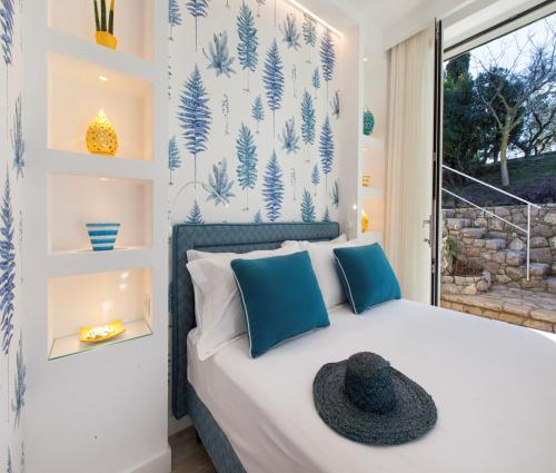 una camera da letto con un letto con un cappello nero sopra di AMORE RENTALS - Resort Ravenna - The Villa a Massa Lubrense