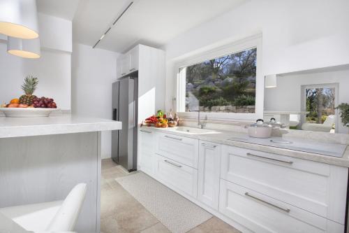eine weiße Küche mit einem Waschbecken und einem Fenster in der Unterkunft AMORE RENTALS - Resort Ravenna - The Villa in Massa Lubrense