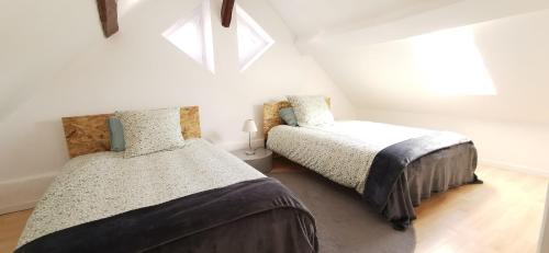 two beds in a attic bedroom with two windows at Maison charmante aux portes de Tours et des châteaux in Saint-Avertin