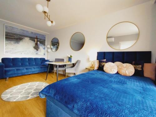 a bedroom with a blue bed and a table and chairs at Śląska 12 by Perfect Apart in Gdańsk