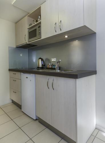 a kitchen with white cabinets and a sink and a microwave at 166 Majestic Court Motel in Christchurch