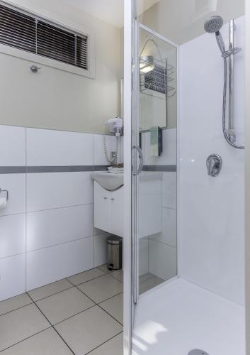 a white bathroom with a shower and a sink at 166 Majestic Court Motel in Christchurch