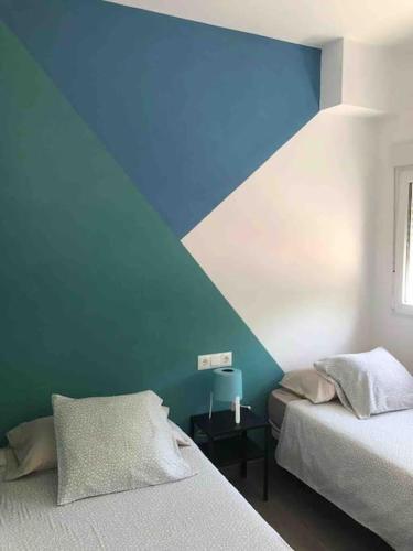 a bedroom with two beds and a blue wall at La Carihuela Apartamento in Torremolinos