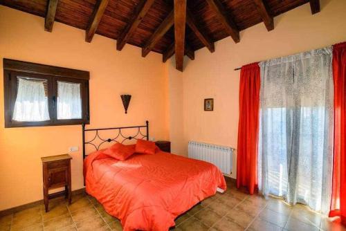 a bedroom with a bed with red sheets and windows at Casas Rurales Trefacio in Trefacio
