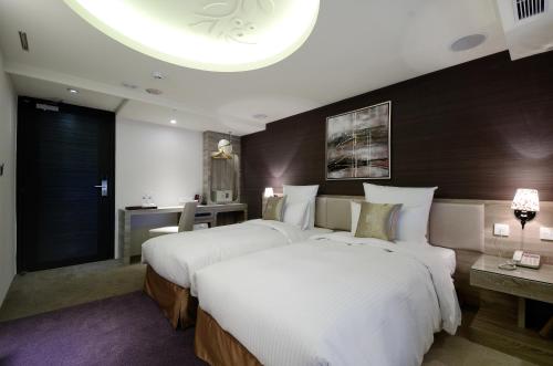 a hotel room with two beds and a desk at V-one Vogue Hotel in Taipei