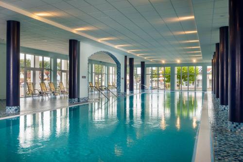 ein großer Pool in einem Gebäude mit Stühlen in der Unterkunft Precise Resort Hafendorf Rheinsberg in Rheinsberg
