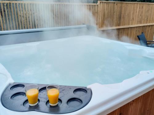 two glasses of orange juice sitting on a hot tub at Projekt ŚWIT - domki z prywatną jacuzzi i sauną in Żywiec
