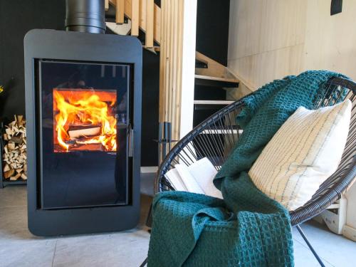 a fireplace in a room with a chair with a blanket at Projekt ŚWIT - domki z prywatną jacuzzi i sauną in Żywiec