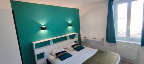 a bedroom with a bed with a green accent wall at Hotel Des Bains in Veulettes-sur-Mer