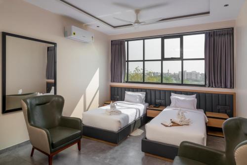 a hotel room with two beds and a chair at Hotel Padmawati Grand in Nānded