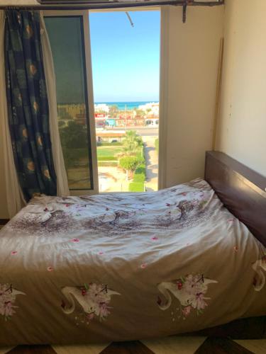 a bed in a room with a large window at SKY Management in Hurghada