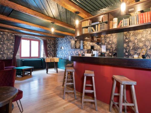 a bar with stools in a room with wooden ceilings at Peanut Medieval Lodge in Saint-Ursanne