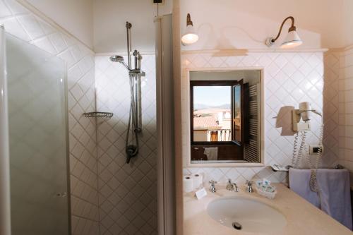 a bathroom with a sink and a shower with a mirror at Valtur Baia dei Pini in Budoni