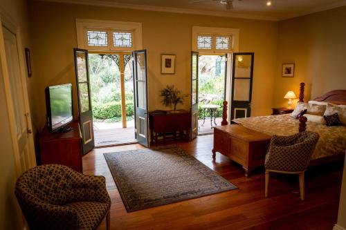 een slaapkamer met een bed en een tafel en een televisie bij Tizzana Winery Bed and Breakfast in Sackville Reach