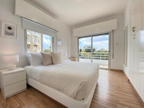 a bedroom with a white bed and a large window at Phaedrus Living Down Town Flat Nestoras 301 in Limassol