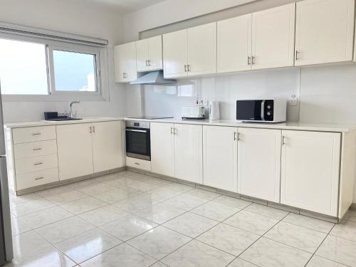 a white kitchen with white cabinets and appliances at Phaedrus Living Down Town Flat Nestoras 301 in Limassol