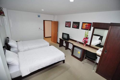 a bedroom with two beds and a desk with a television at Man u Apartment in Chaiyaphum