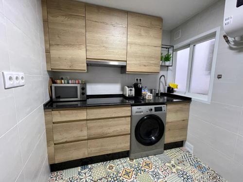 a small kitchen with a washer and a microwave at Casa da Fonte in Ourense